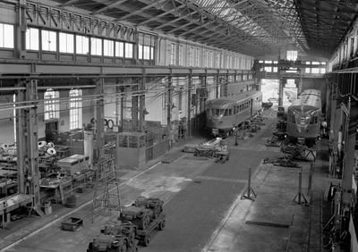 839705 Interieur van de hoofdwerkplaats van de N.S. te Haarlem: loods met enkele diesel-electrische treinstellen DE1 / ...